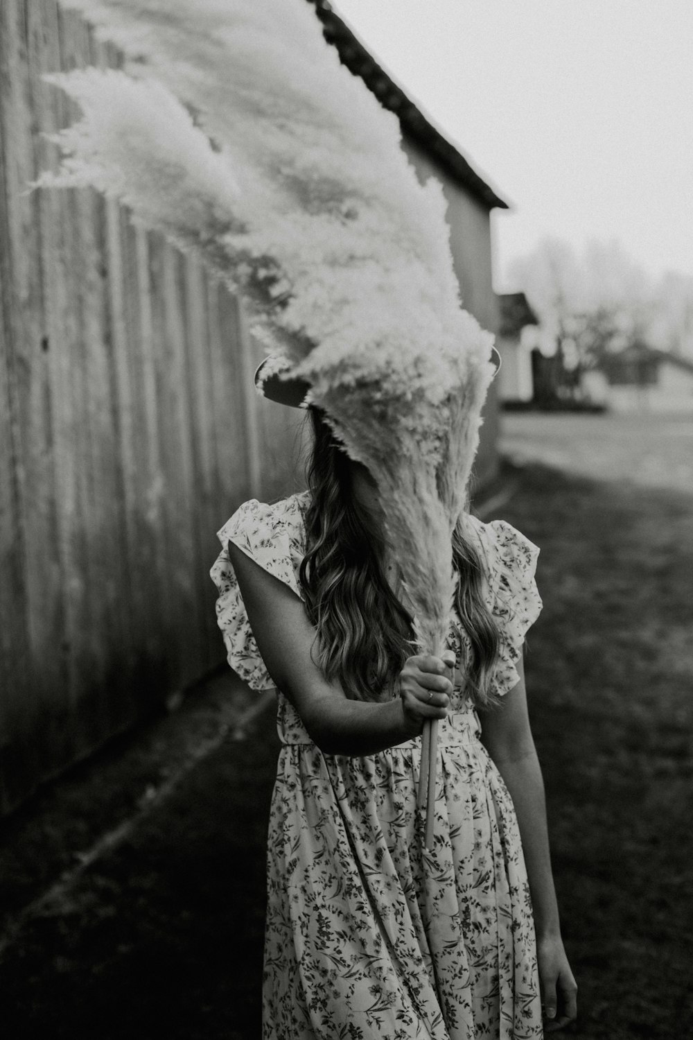 grayscale photo of woman in floral dress holding white textile