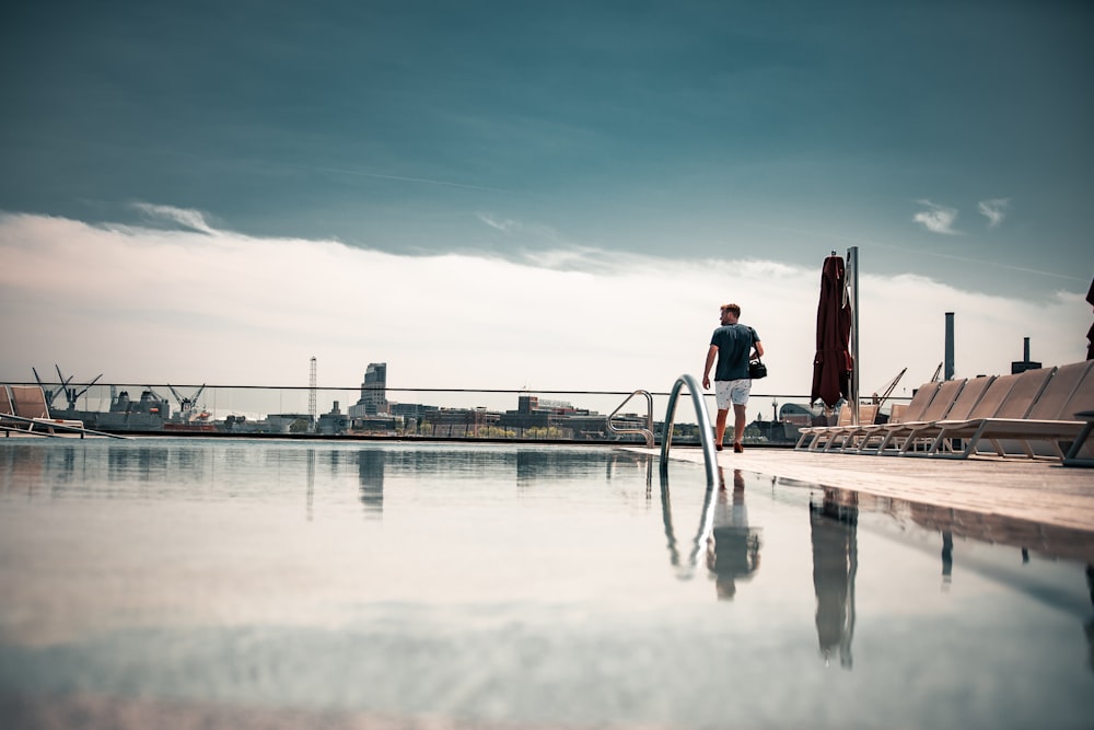 homme en chemise bleue debout sur le quai pendant la journée