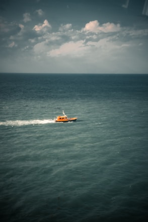 orange and white boat on sea during daytime