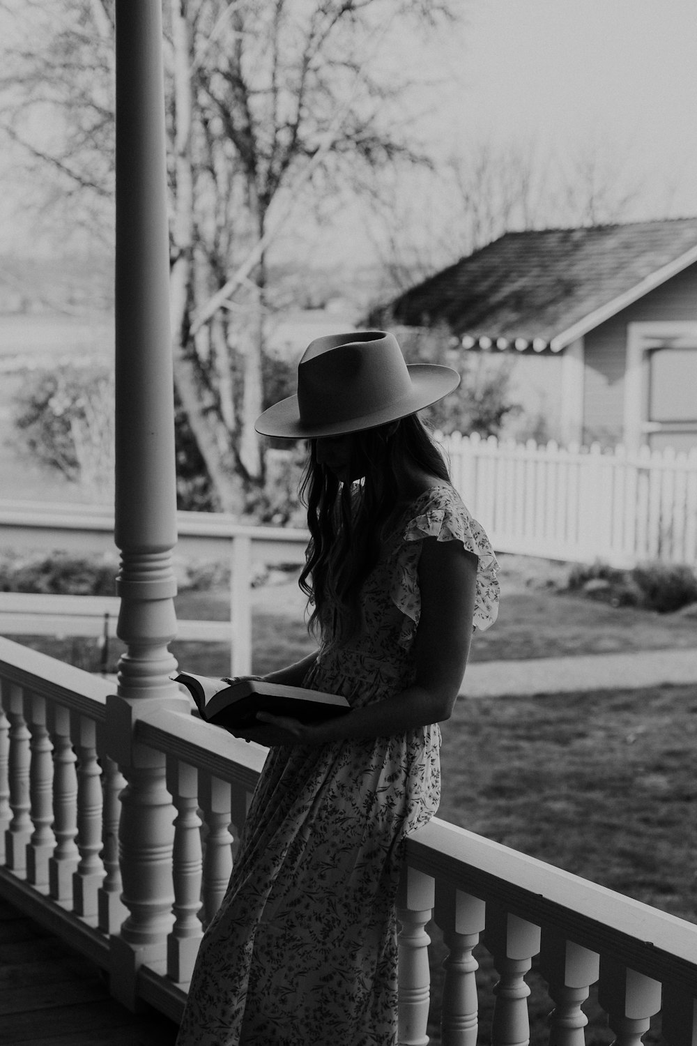 꽃 드레스와 모자를 쓴 여자의 회색 사진 나무 벤치에 앉아