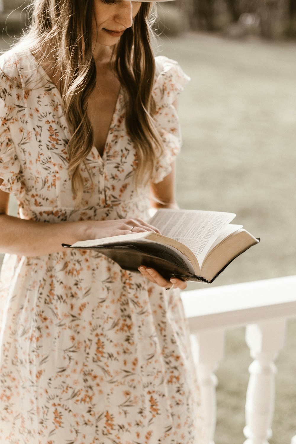 woman in white and brown floral dress reading book