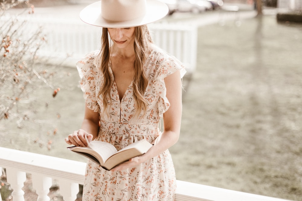 Femme en robe fleurie blanche et marron portant un chapeau blanc