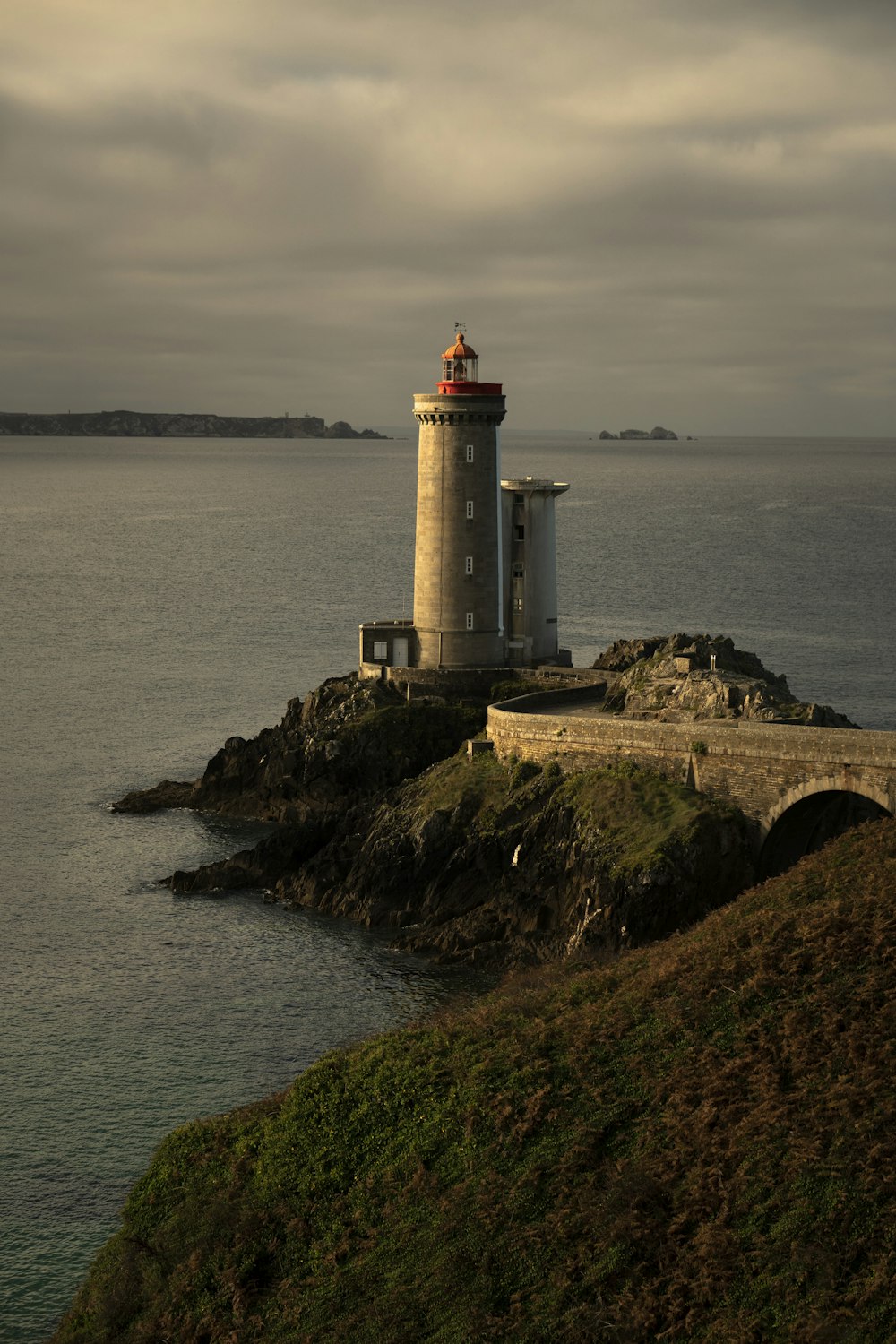 Weißer und brauner Leuchtturm auf brauner Felsformation in der Nähe von Gewässern tagsüber