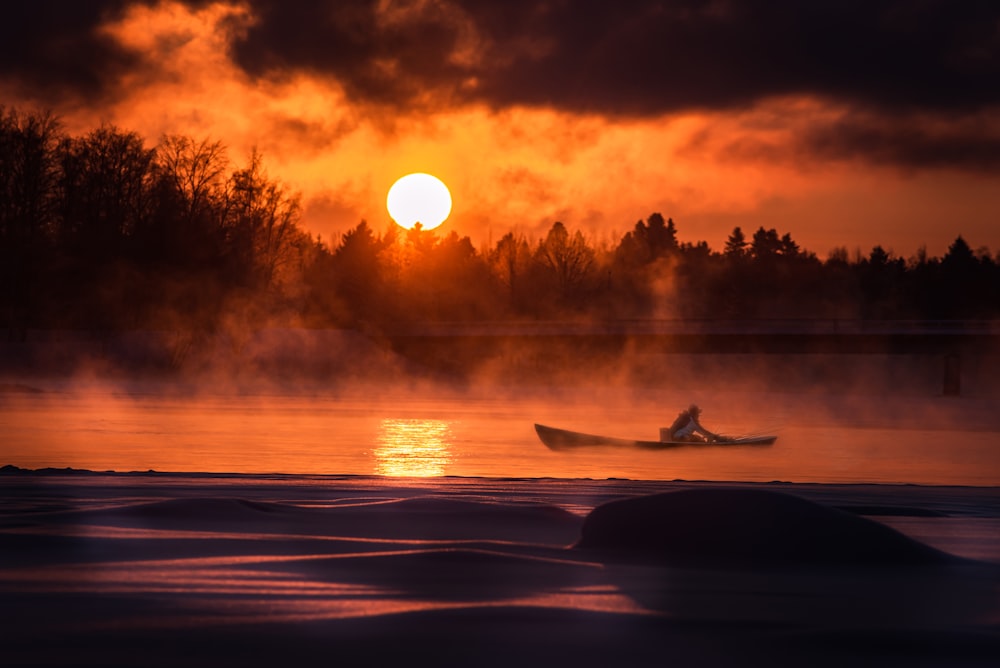 silhouette of person riding surfboard during sunset