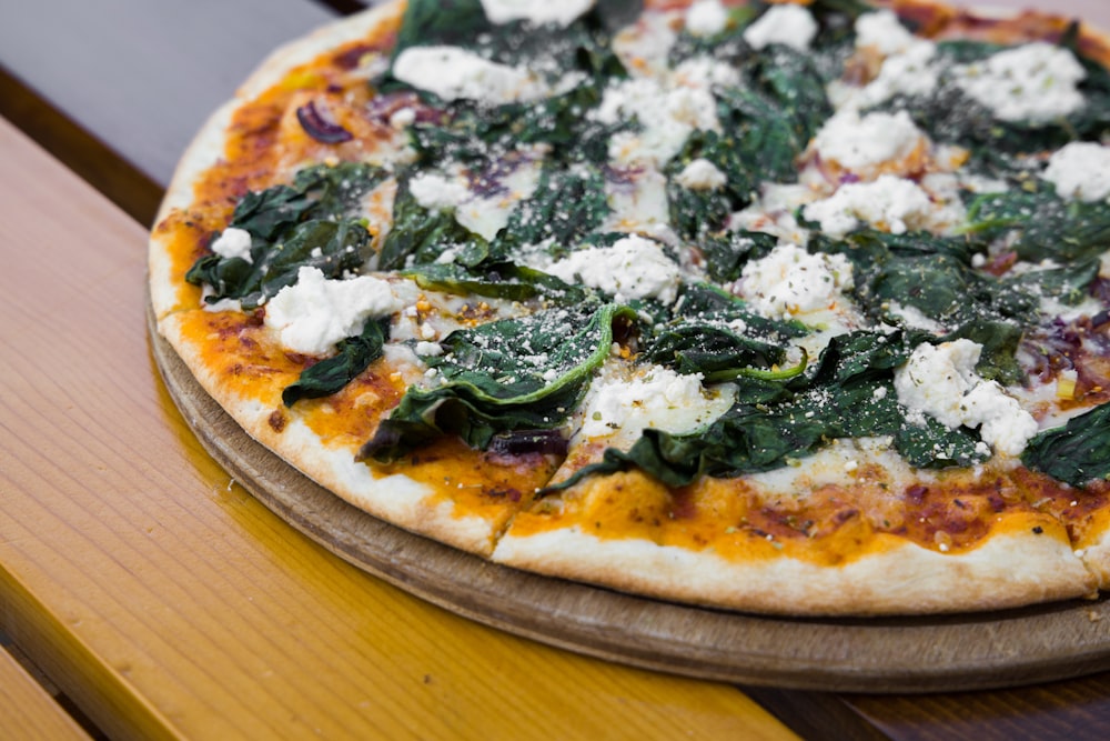 pizza with green leaves on brown wooden table