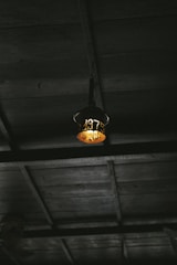 Decorative iron lantern hanging from a rustic wooden beam with soft light inside.