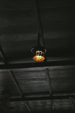 Decorative iron lantern hanging from a rustic wooden beam with soft light inside.