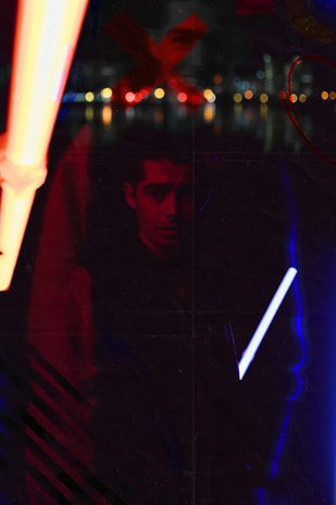 Artistic shot of Franc Sebasti under colorful neon lights in a minimalistic urban setting