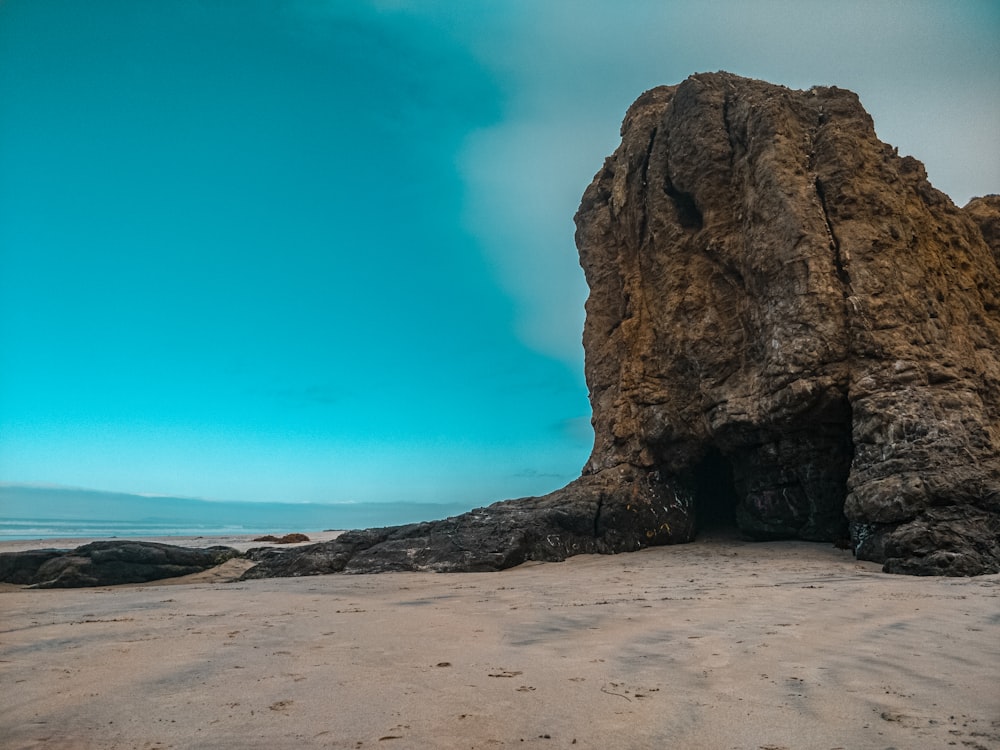 brown rock formation on brown sand under blue sky during daytime