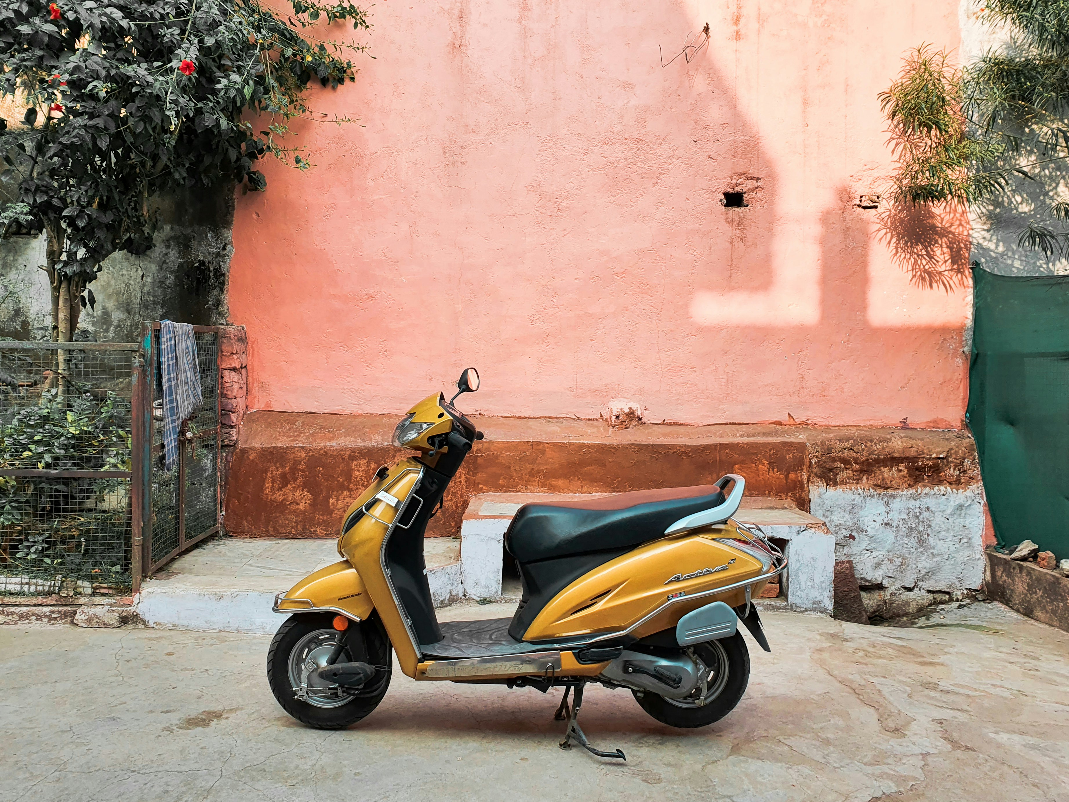 foto-motoneta-amarilla-y-negra-estacionada-junto-a-un-muro-de-hormig-n