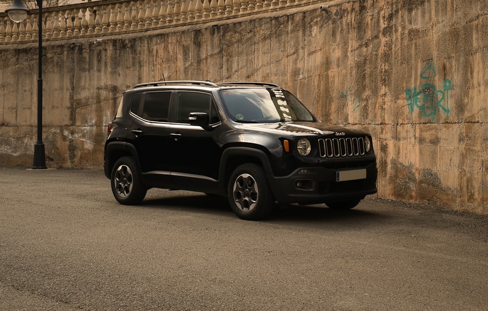 black suv parked beside brown wall