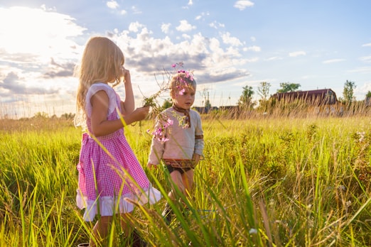 girl in pink and white dress standing on green grass field during daytime