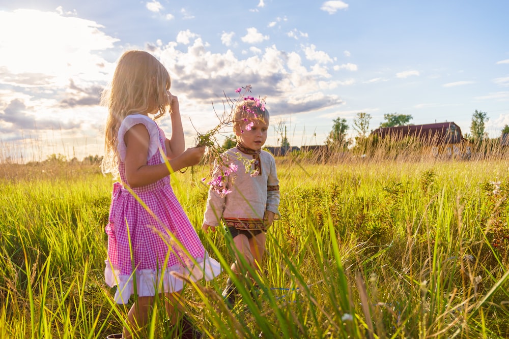 낮 동안 푸른 잔디밭에 서 있는 분홍색과 흰색 드레스를 입은 소녀