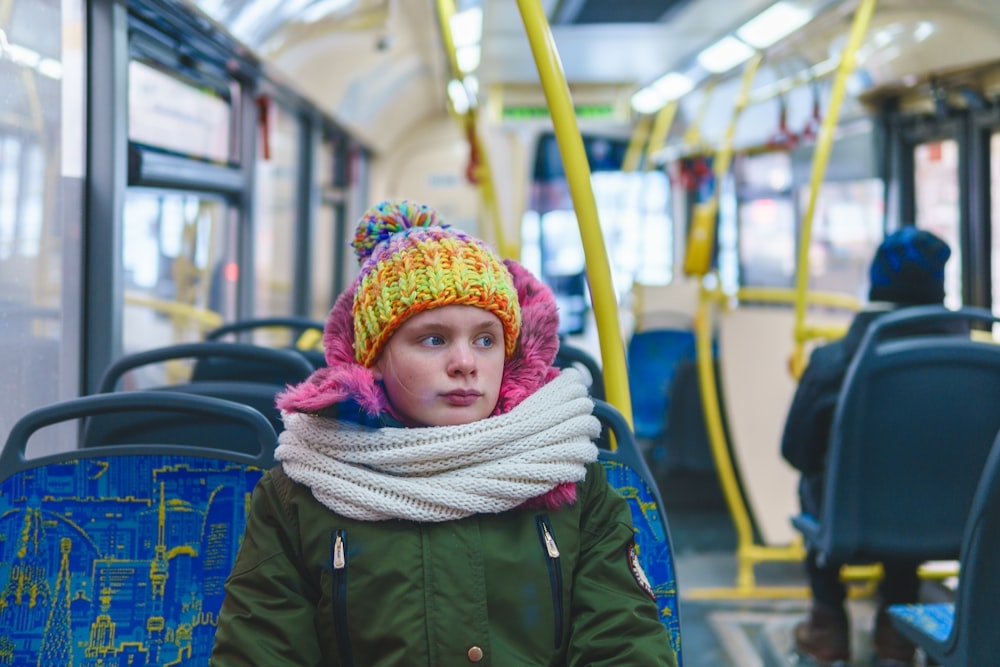 woman in green jacket wearing red and white knit cap