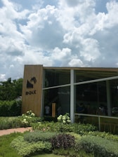 A sleek modern garden cube office surrounded by lush greenery on a sunny day.