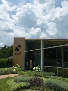 A modern luxury prefabricated bungalow surrounded by lush greenery under a clear blue sky.