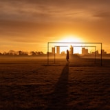 silhouette of person standing on field during sunset