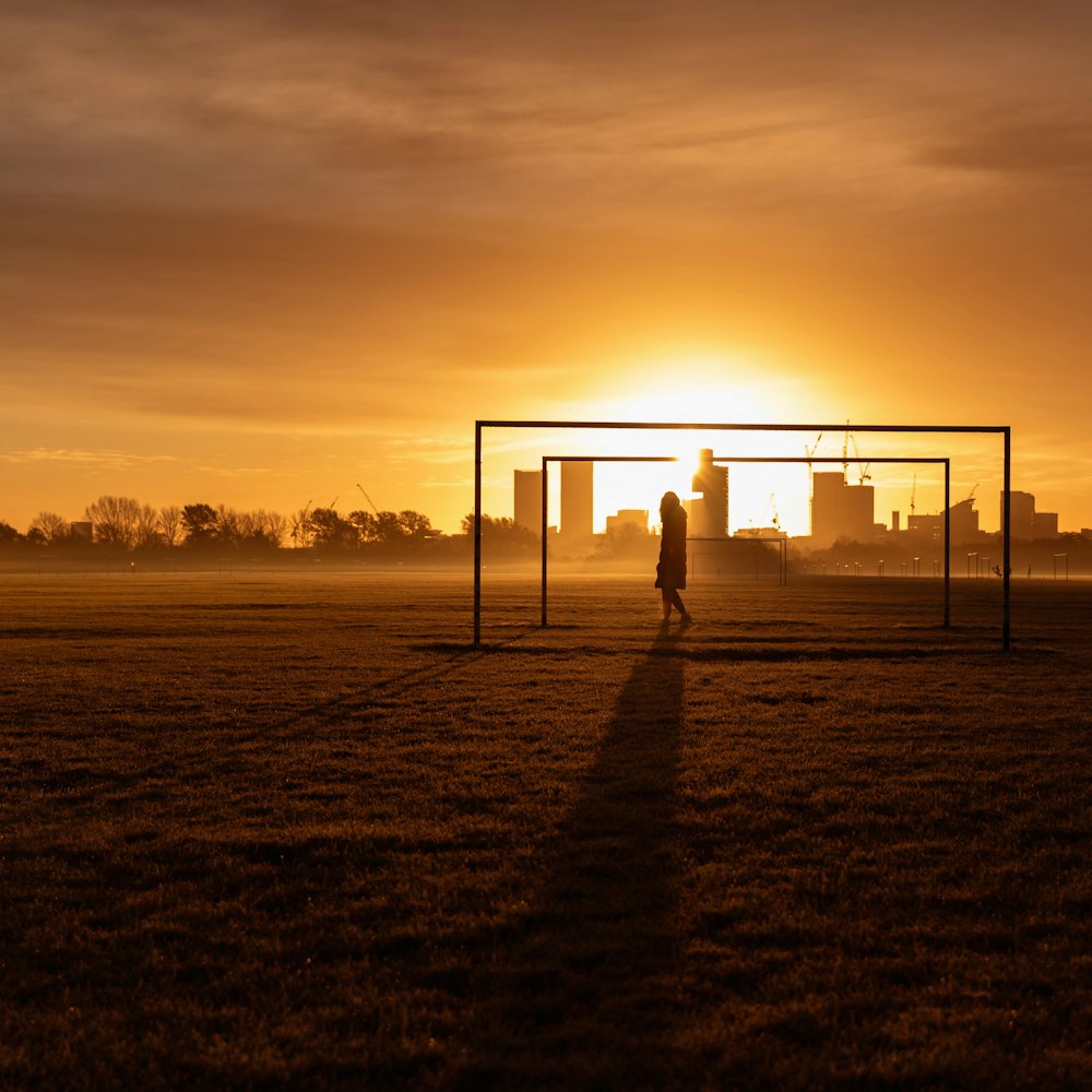 Silueta de la persona de pie en el campo durante la puesta del sol