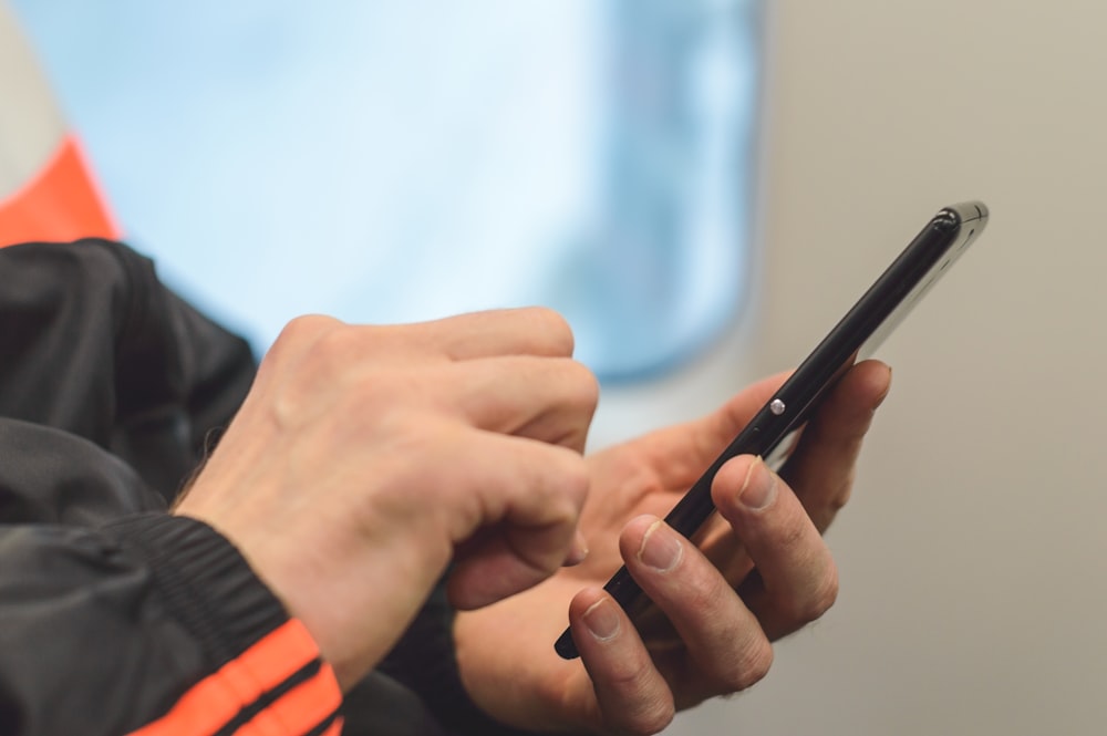 person in black and orange long sleeve shirt holding black pen