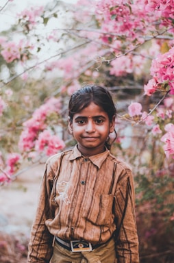 boy in brown button up shirt standing near pink flowers during daytime