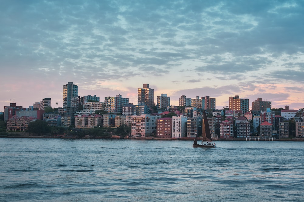 a sailboat in a body of water with a city in the background