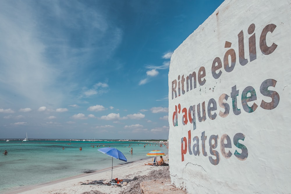 white and blue beach signage on beach during daytime