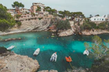 people in white and orange boat on water near brown rock formation during daytime