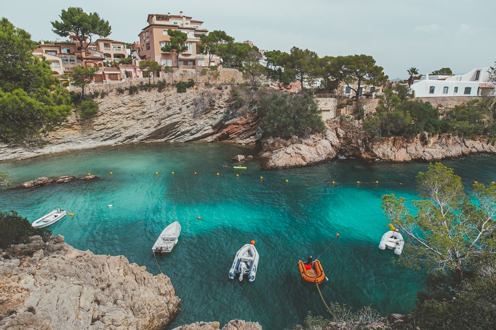 낮 동안 갈색 암석 근처의 물 위에서 흰색과 주황색 보트를 탄 사람들