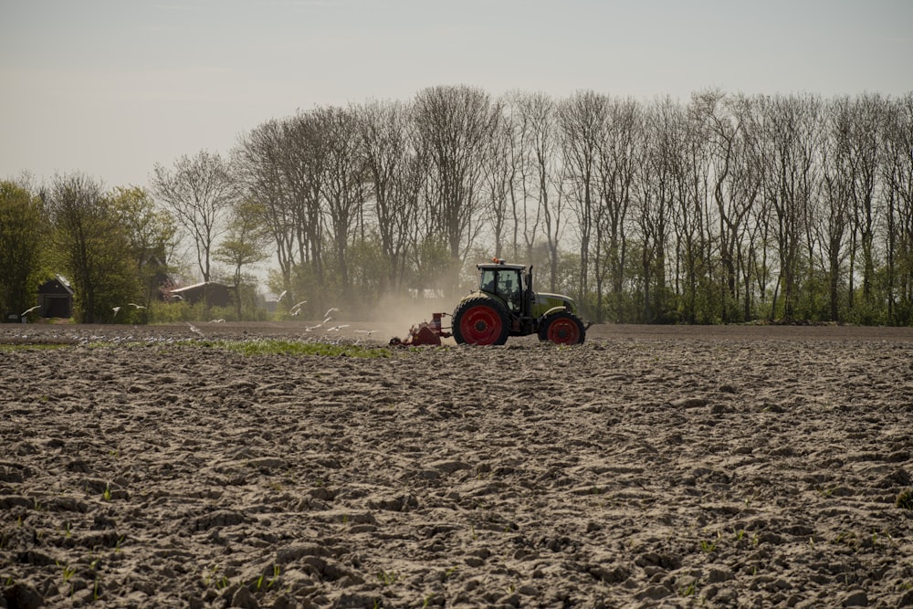 green and orange tractor on brown field during daytime