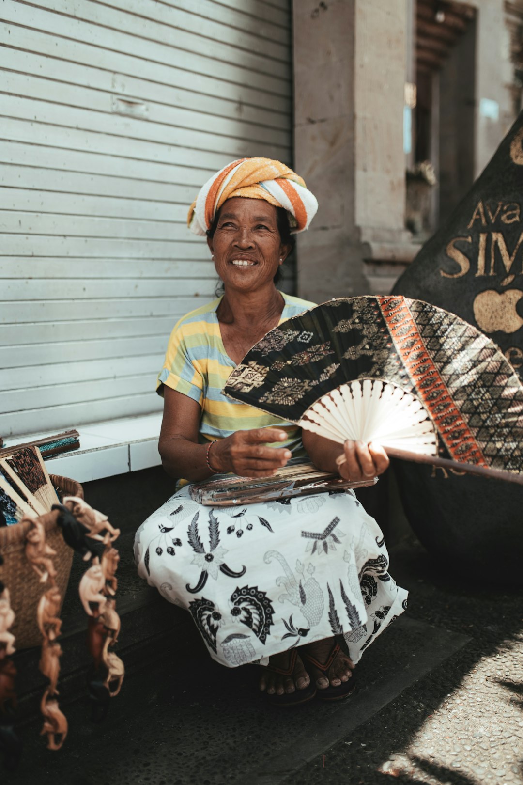 woman in yellow and black shirt holding white and black hand fan