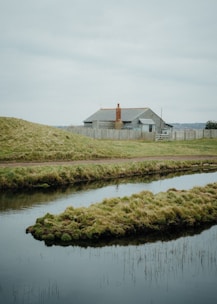 A serene landscape with a for-sale sign in front of a quaint cottage.