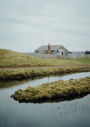 A serene landscape with a for-sale sign in front of a quaint cottage.