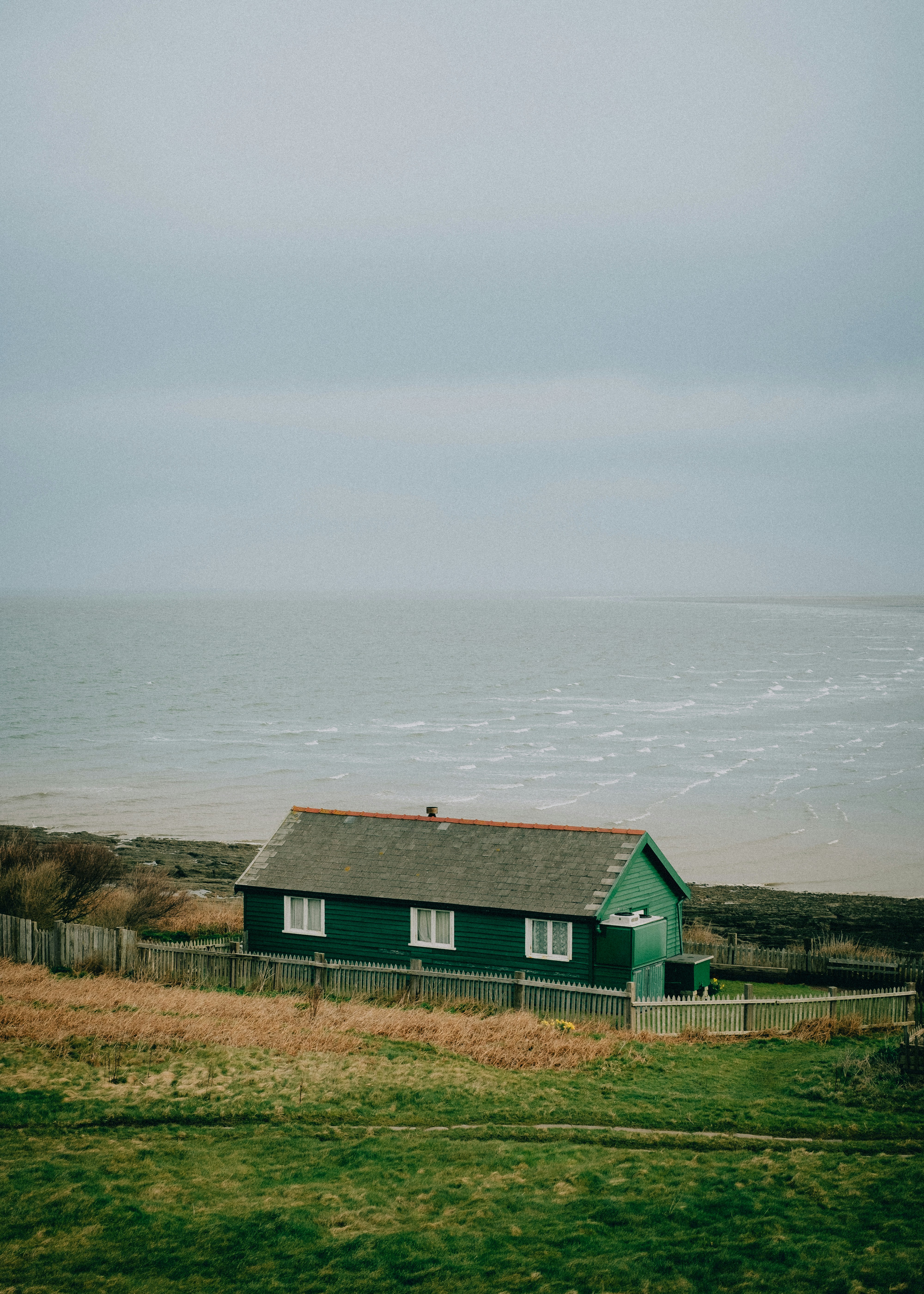green and brown house near body of water during daytime
