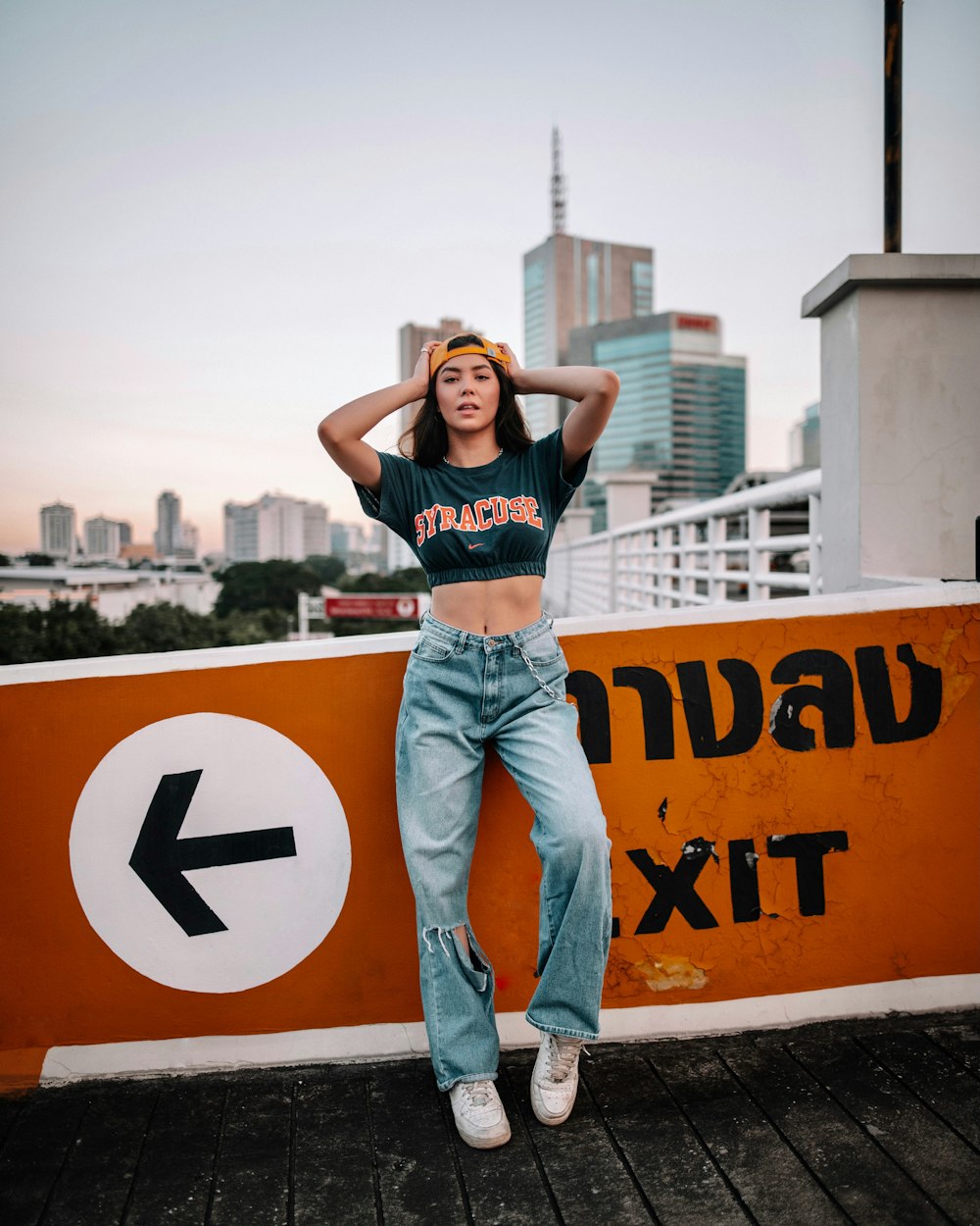 woman in black tank top and blue denim jeans standing on yellow and black road sign