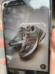 An e-commerce seller using megure on a phone to measure a pair of shoes for an online listing.