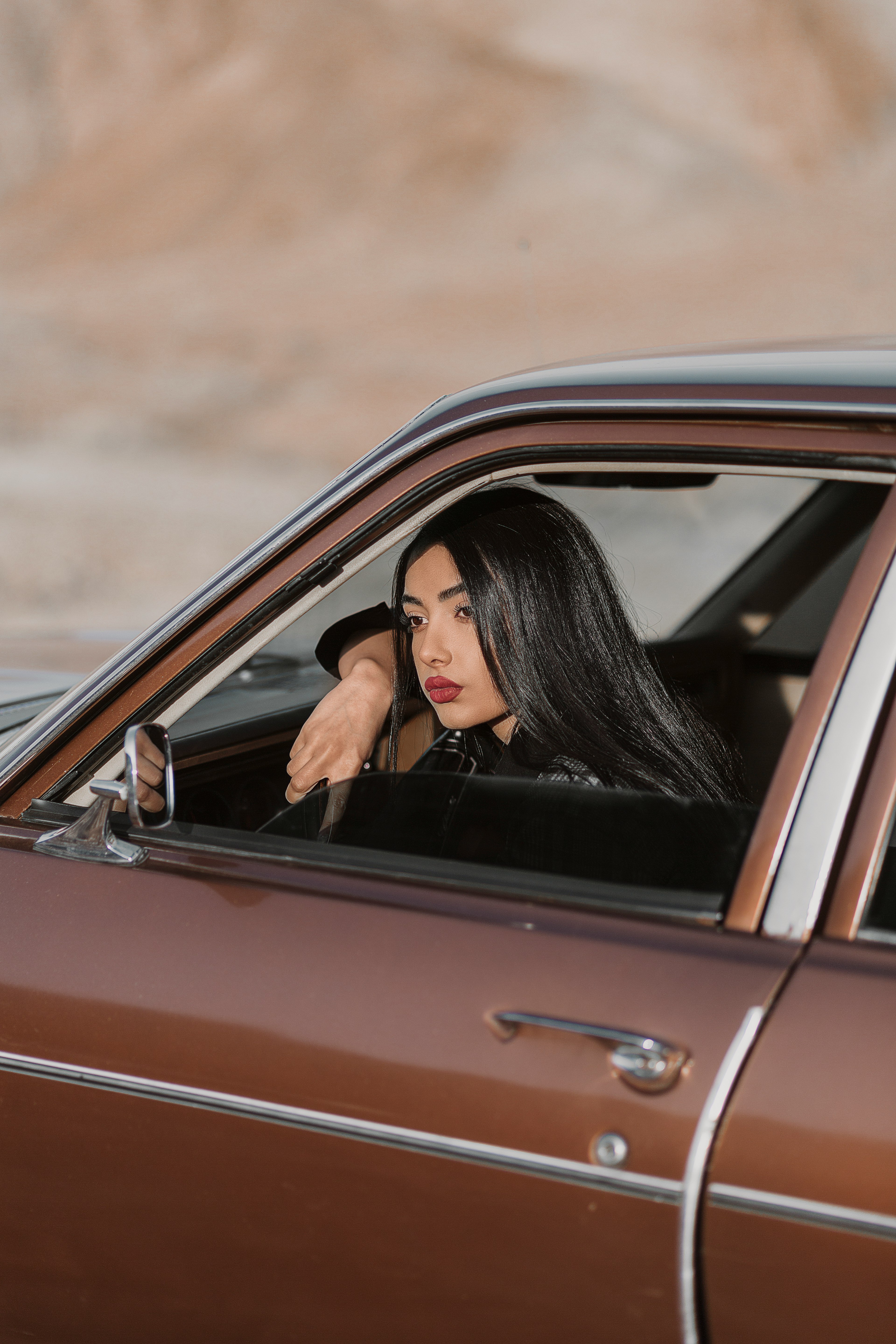 woman in black long sleeve shirt leaning on red car during daytime