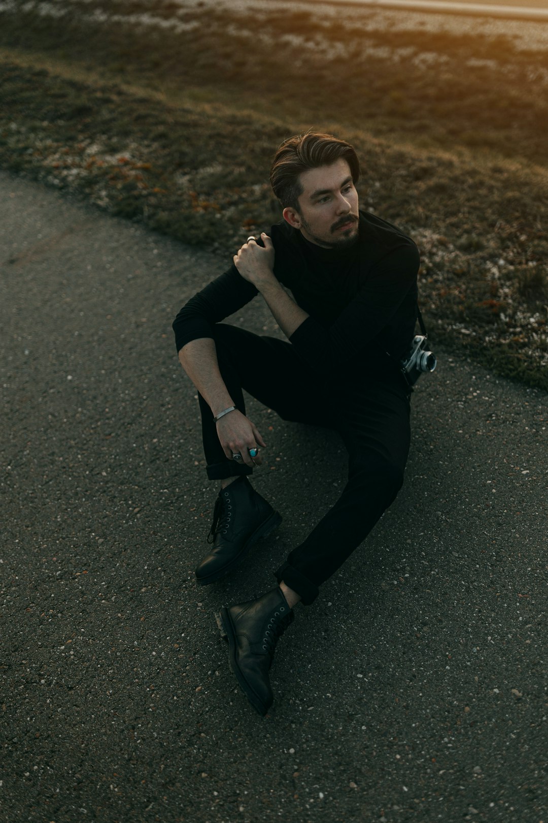 woman in black shirt and black pants sitting on asphalt road