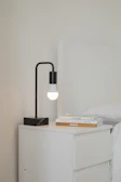 Modern small apartment setup featuring the side table next to a bed with soft lighting.