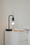 Modern nightstand with drawers holding a bedside lamp and a stack of books