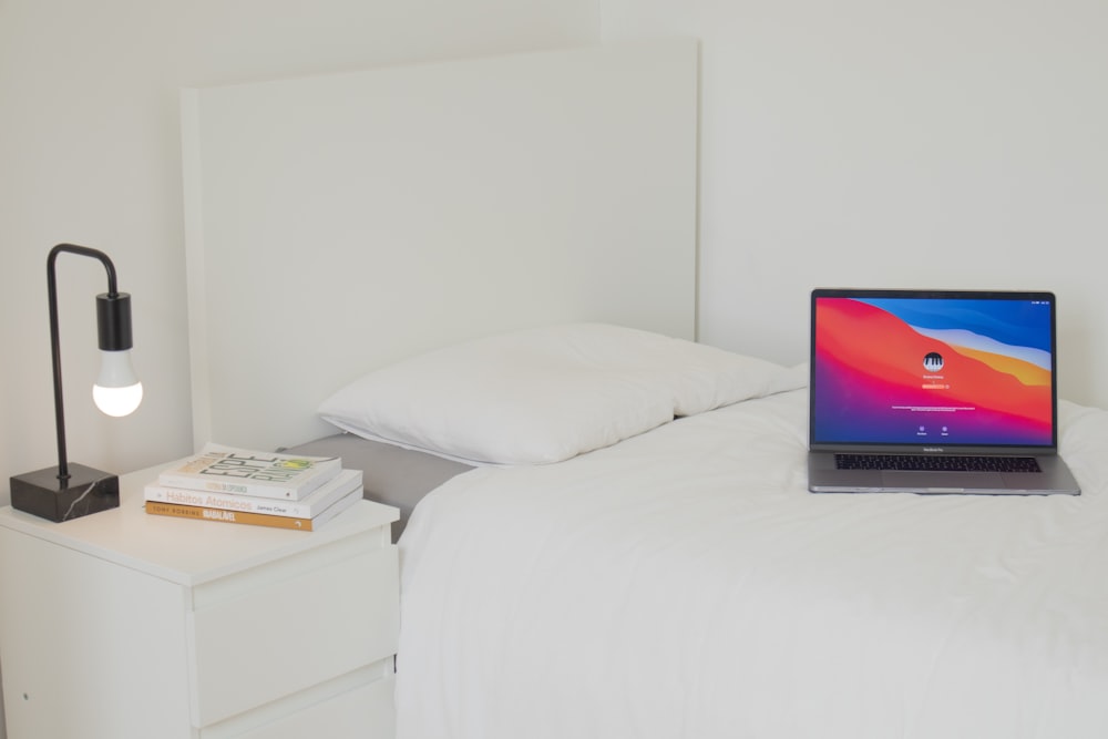 black laptop computer on white bed
