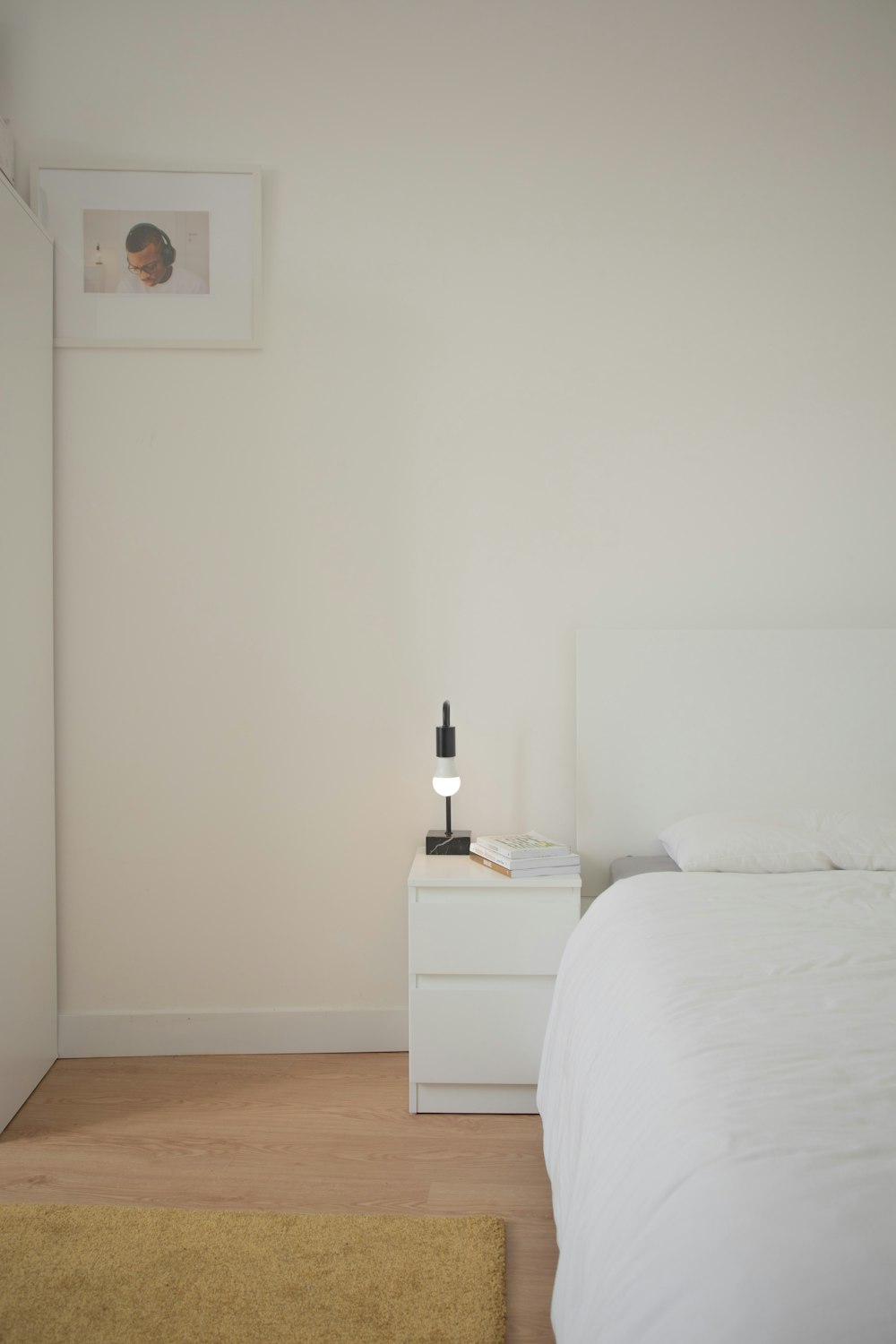 white bed linen beside white wooden nightstand