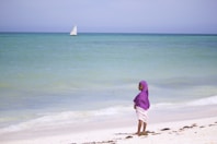woman in purple hijab standing on beach during daytime