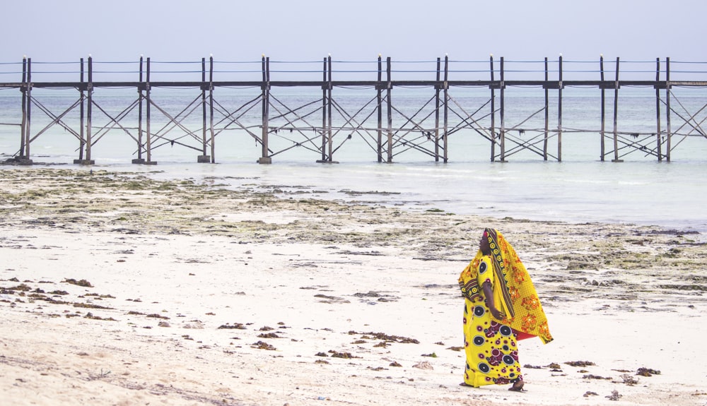 woman in yellow and black floral dress standing on beach during daytime