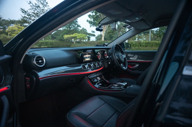 A sleek black luxury car interior illuminated by soft blue ambient lighting, reflecting modern sophistication.
