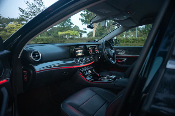 Close-up shot of a sleek black luxury car dashboard illuminated by subtle gold accent lighting, evoking power and precision.