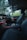 The interior of a luxury car features modern black leather seats and a sleek dashboard with illuminated controls. The ambient lighting along the dashboard adds an elegant touch, while the outside view through the windows reveals a green, leafy landscape.