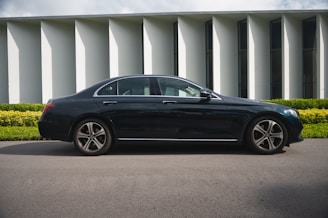 black sedan parked near white building
