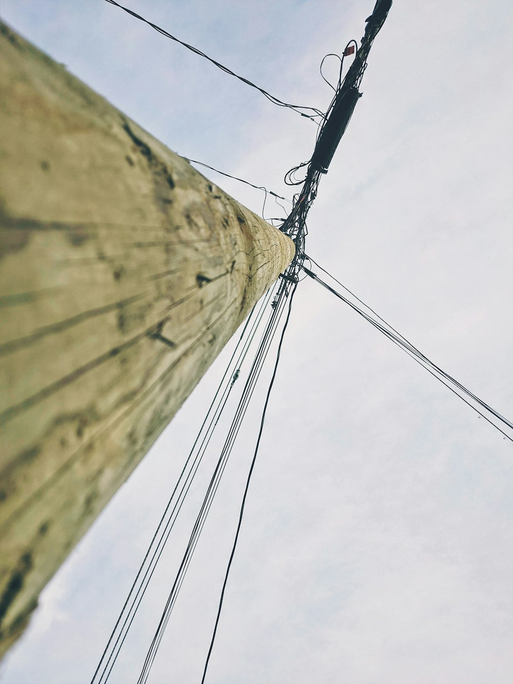 low angle view of brown wooden post under cloudy sky during daytime