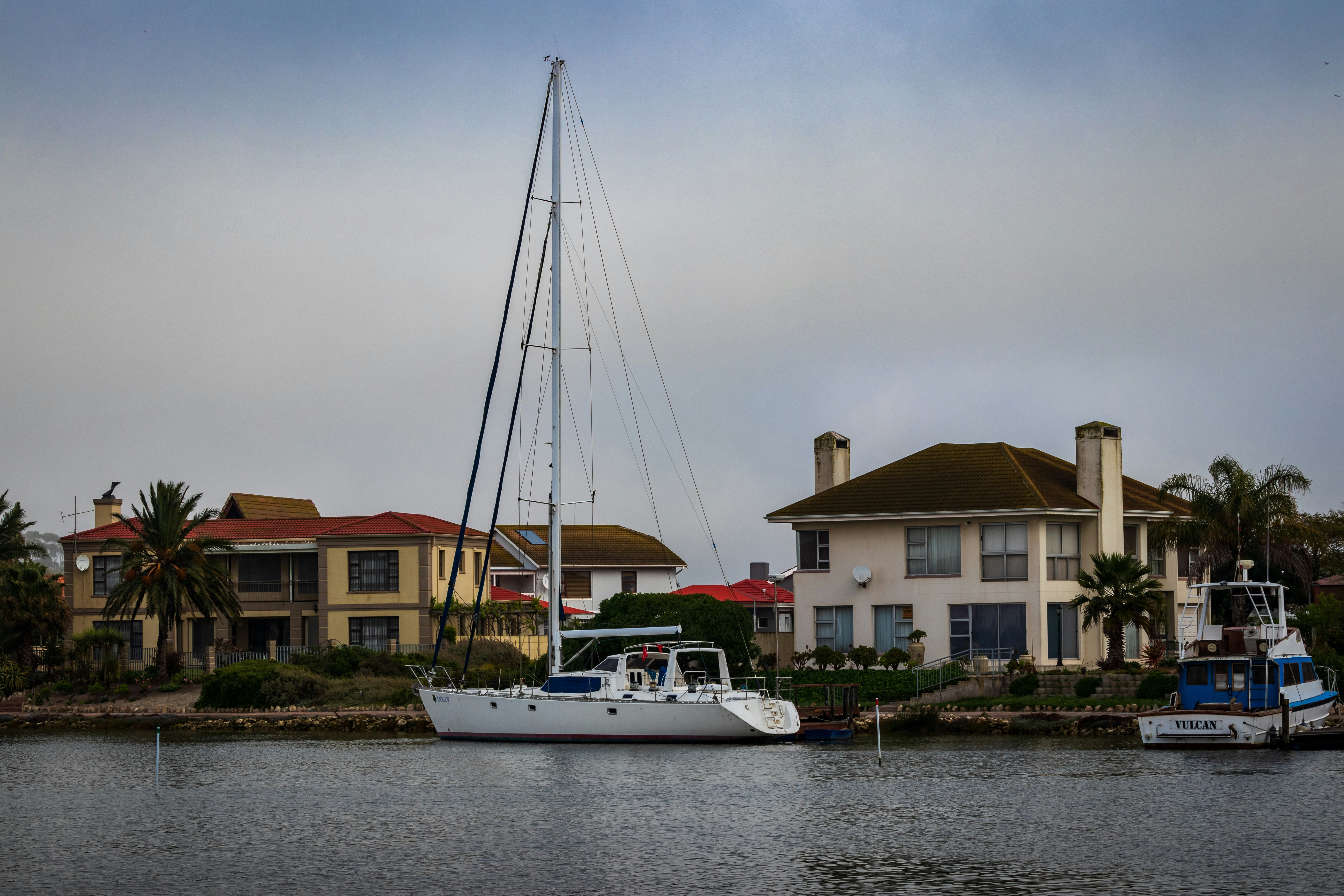 Luxury homes with a yacht on a marina on a cloud day