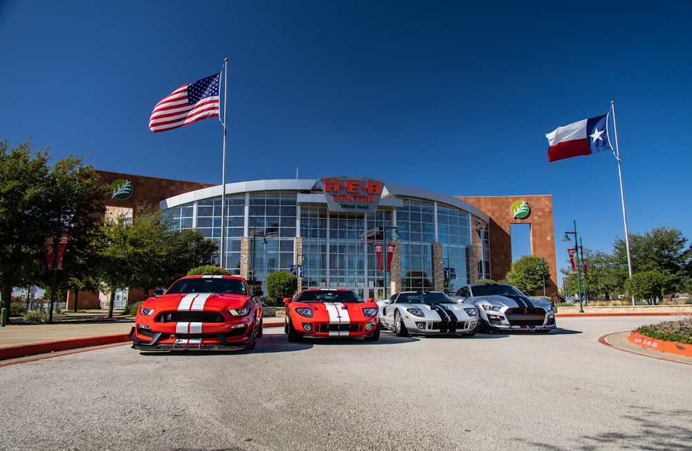 red and black coupe parked beside american flag during daytime